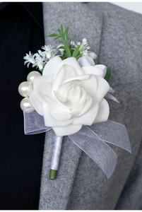 Close-up of white silk rose boutonniere with pearls and organza bow on grey tweed suit