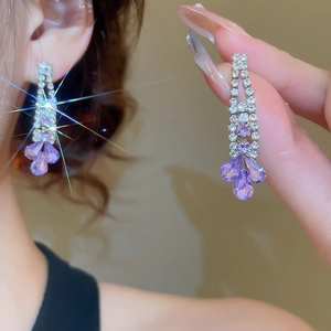 Close-up of elegant silver tassel earrings with purple petals and sparkling stones