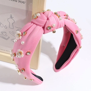 Detail of pink fabric headband with faux pearls, crystal rhinestones and small white flowers