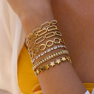 Détail de bracelets superposés en acier inoxydable plaqué or avec zircons et étoiles