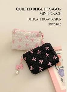 Close-up of pleated cosmetic bags with pink bow prints and pearl charm details