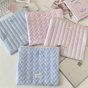 Detailed close-up of quilted heart laptop sleeves with bows and brand label design