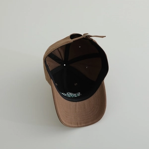 Close-up of adjustable metal buckle and stitching on brown cotton baseball cap