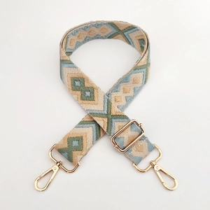 Close-up of geometric diamond jacquard weaving and gold metal hooks on a wide bag strap