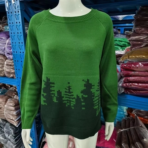 Detail of crew neck green knit sweater featuring dark forest and tree pattern on hem