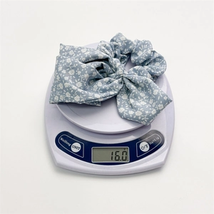 Light blue floral bow hair scrunchie shown on a digital scale weighing 16.0g