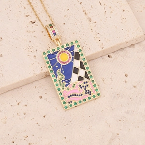 Macro shot of 18K gold tarot pendant with colorful enamel sun and green zircon border