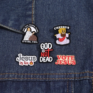 Detailed view of religious themed enamel pins set on dark blue denim background