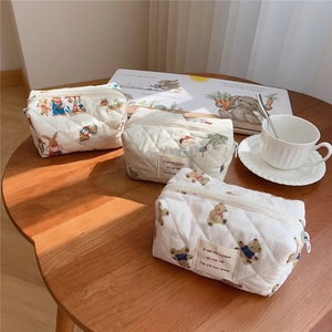 Quilted cotton cosmetic bags with cute bear prints on a wooden table with coffee cup