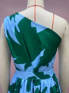 Detailed view of digital leaf print on one-shoulder maxi dress with silky texture