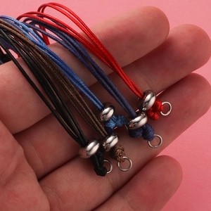 Close-up of adjustable woven cord bracelets in black, red, navy, and brown with metal beads