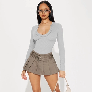 Detail of grey ribbed knit long sleeve top with metal buckle and khaki pleated mini skirt