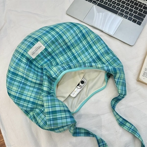 Detail view of green plaid canvas tote showing zipper closure and spacious interior