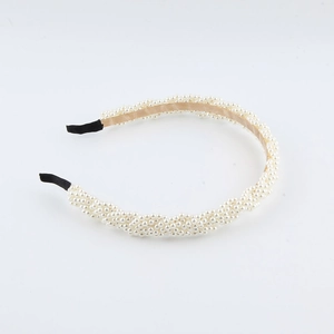 Close-up of elegant woven white pearl headband with wavy texture and non-slip black tips
