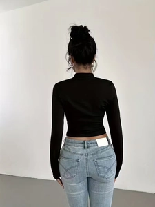 Vue arrière d'un crop top noir moulant avec col montant élégant et tissu élastique