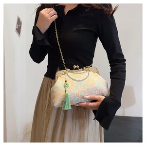 Detailed close-up of embroidered handbag featuring vintage metal clasp and green tassel
