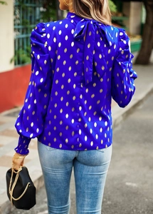 Detail of blue blouse with gold polka dots featuring a decorative back neckline bow tie