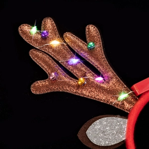 Macro detail of glowing LED reindeer antlers with colorful sequins and small metal bells