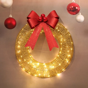 Detail of gold Christmas wreath with red glitter bow and warm LED lights decoration