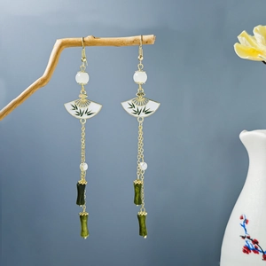 Detail of vintage bamboo tassel earrings with fan-shaped motifs on a natural branch