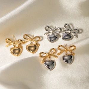 Bowknot heart earrings in gold, silver and bicolor finish on ivory silk background