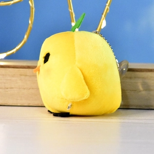 Side view detail of a soft yellow chick plush keychain with a green sprout on top