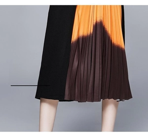 Détail de jupe plissée en tricot montrant un dégradé orange et marron zigzaguant
