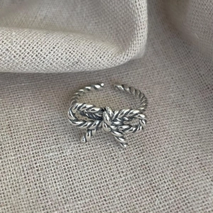 Detailed close-up of a 925 sterling silver bow ring with twisted rope texture on fabric