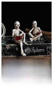 Detail of hand-painted resin skeleton figurines reading on vintage books for Halloween decor