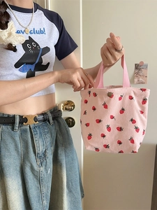 Sac à bandoulière en velours côtelé rose avec motif fraises tenu par un mannequin chic