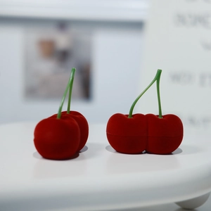 Detalle del joyero de cereza roja en terciopelo para anillos con textura suave