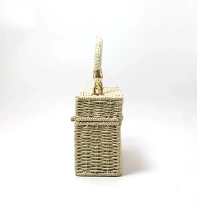 Close-up of beige woven box bag with textured straw pattern and gold metal hardware