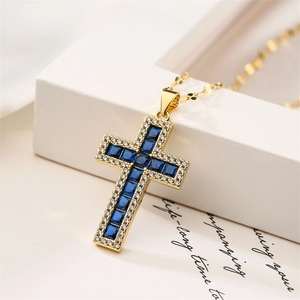 Macro shot of gold cross necklace with deep blue gems and micro-paved zircons