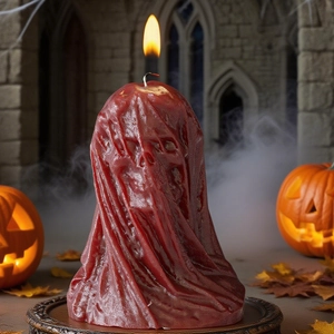 Halloween hooded skeleton candle with red cloak design and warm glowing candle flame