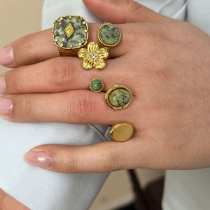 Set of gold stainless steel rings with green natural stones on woman's hand