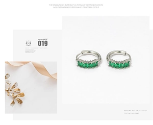 Macro detail of silver-colored earrings featuring five rectangular emerald-green zircons