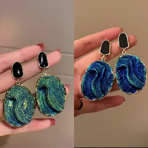 Detail of oil-dripping oval earrings changing from blue-green to deep blue tones