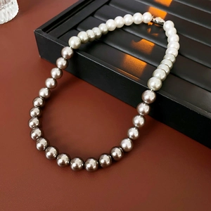 Close-up of gradient pearl necklace from dark grey to silver on a black display tray