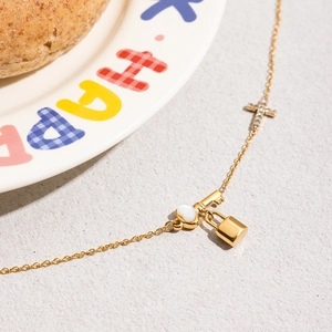 Gros plan du collier en acier inoxydable doré avec breloques clé, cœur, cadenas et croix