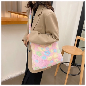Detailed view of plush tote bag with colorful flower patterns worn over the shoulder