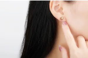 Close-up of elegant champagne pearl stud earring worn by a model on the earlobe