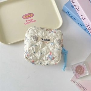 Detail of quilted beige storage bag with cartoon elephant print and blue zipper pull