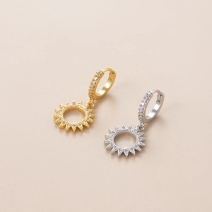Detail of sun-shaped earrings in gold and silver with sparkling zircon pavé setting