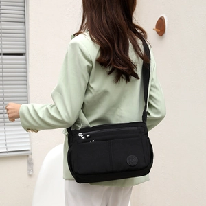 Bolso bandolera de nailon negro con múltiples bolsillos visto desde un lateral