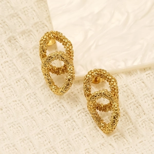 Golden double-loop oval earrings with textured hammered finish on a white background