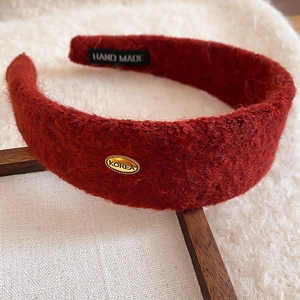 Détail d'un serre-tête large en peluche rouge avec plaque dorée et étiquette fait main