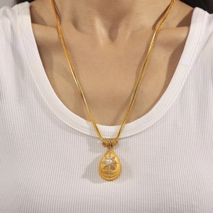 Golden water drop pendant necklace with pearl and starburst texture on snake chain