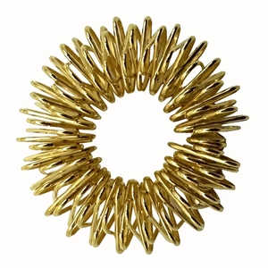Detailed view of the golden metal spring finger massage ring on a white background