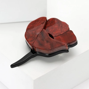 Close-up of acrylic rose flower hairpin with marble texture on a white pedestal
