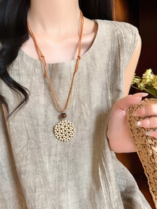 Detailed macro view of long bohemian woven heart necklace with wooden beads on brown cord